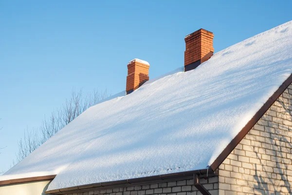 In winter seasons a house roof covered in snow